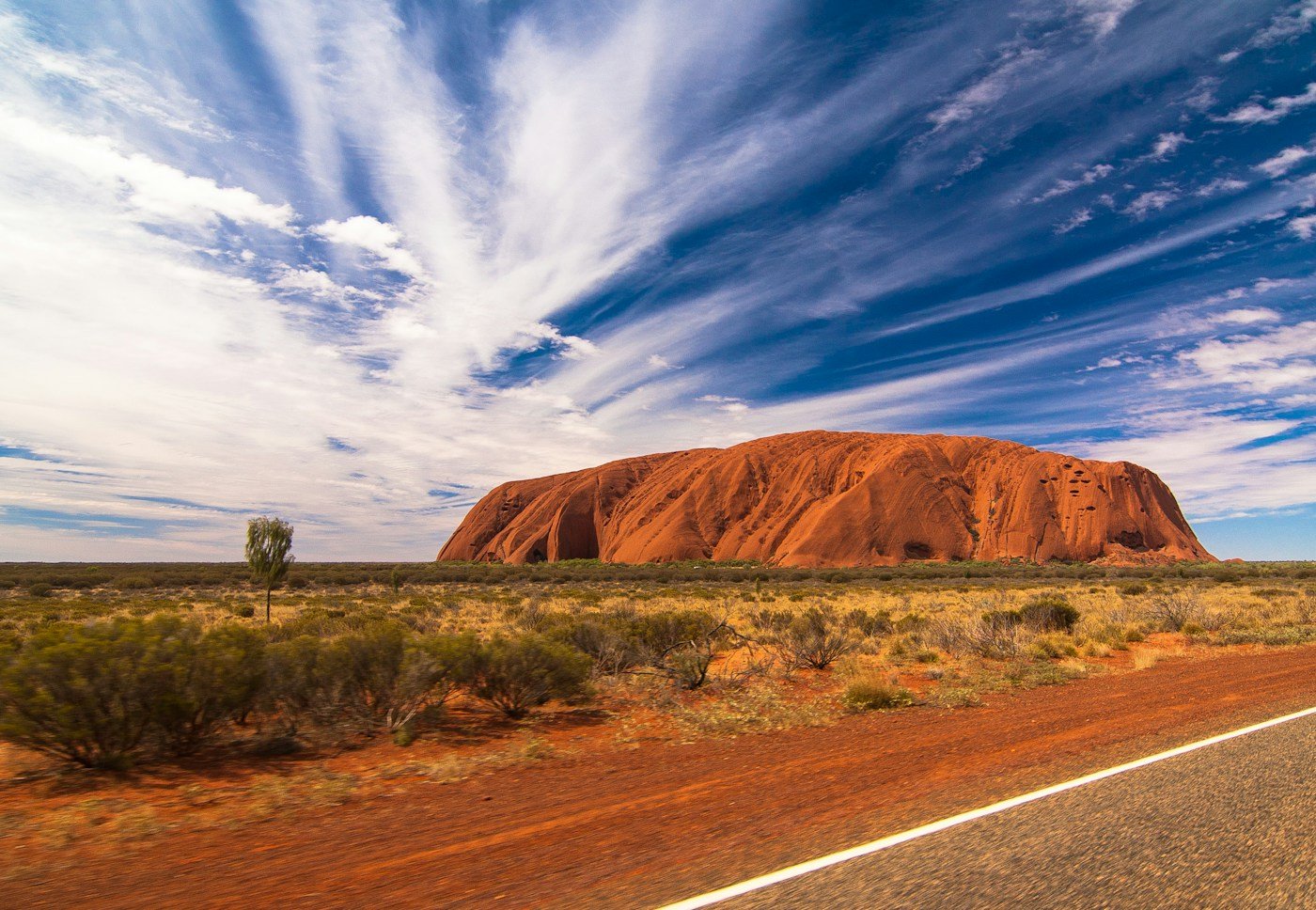Uluṟu rising above the arid landscape beneath a blue sky